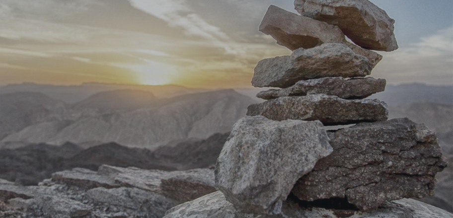 rocks stacked up at top of mountain representing mergers & acquisitions